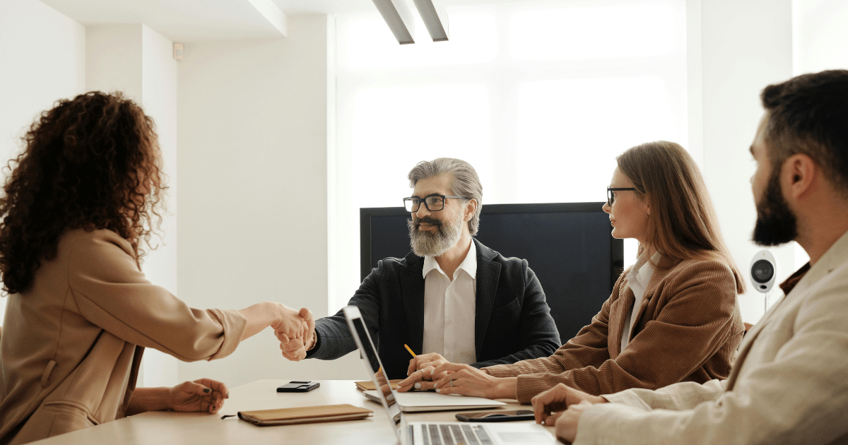 Business professionals shaking hands during a meeting — partnership and collaboration concept by Brilliant Technologies.