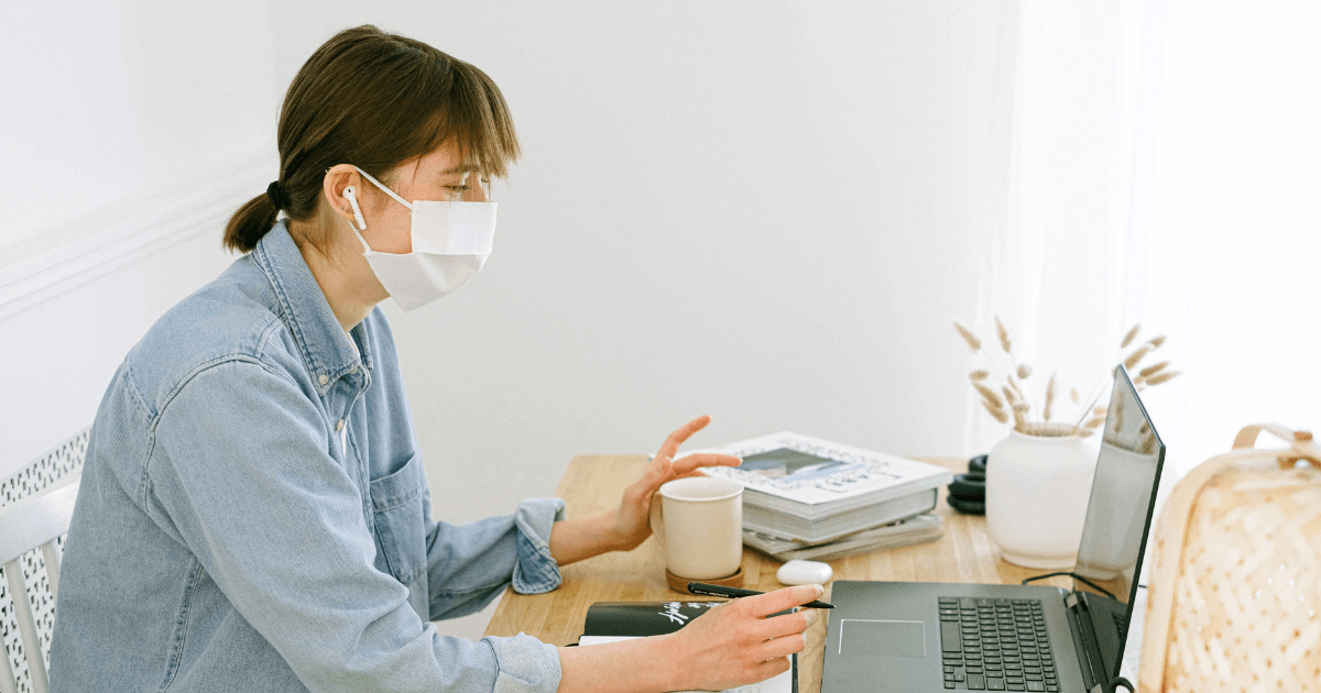 Woman wearing a mask working remotely on a laptop during an online meeting, supported by Brilliant Technologies.