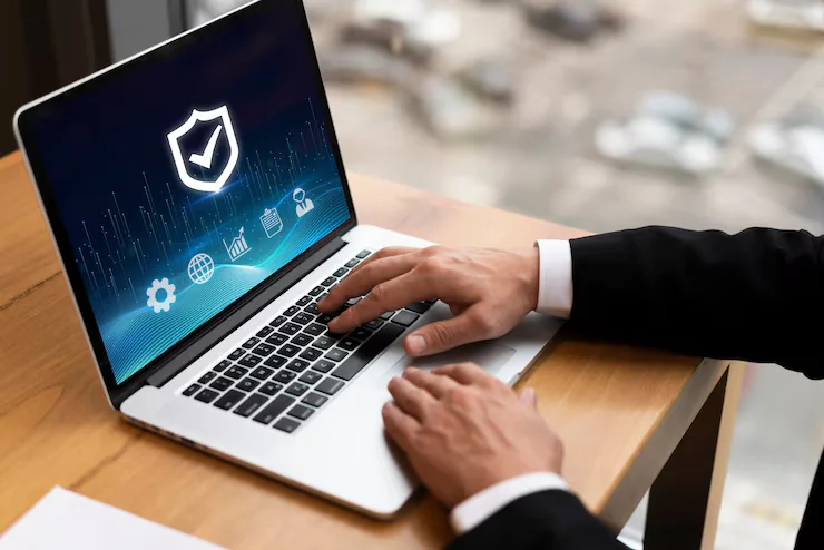 Business professional using a laptop displaying a security shield interface for cybersecurity solutions by Brilliant Technologies.
